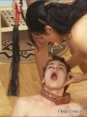 Two brunettes trample a slave and spit into his mouth