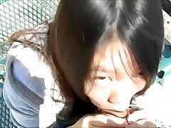 Chinese woman blowing studs in the park in broad day light