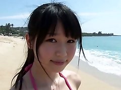Slim Asian girl Tsukasa Arai walks on a sandy beach under the sun