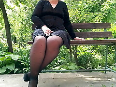 Wild cougar in pantyhose pissing in the park on a bench – rear view