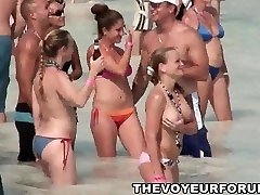 קבוצה של בחורות בקולג ' מראה את הציצים על החוף